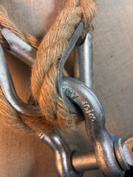 A close-up of a metallic clasp intertwined with thick rope.